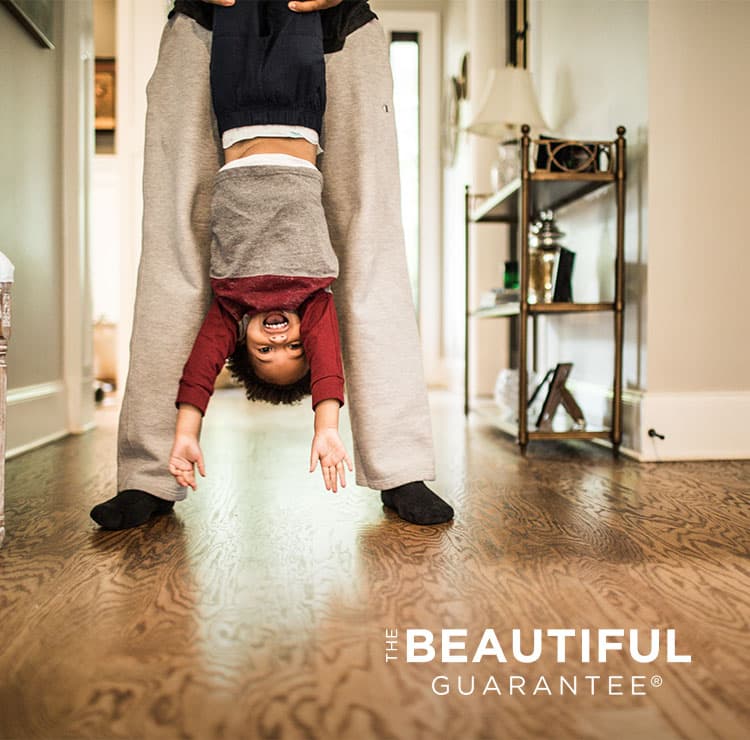 the beautiful guarantee child held upside down above hardwood flooring